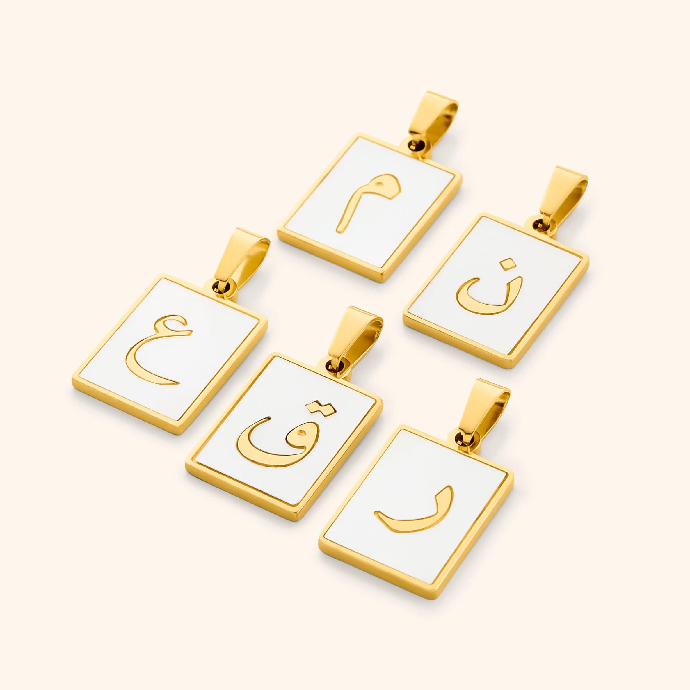 A collection of five Arabic letter charms in 18K gold plating, each featuring an iridescent pearl backdrop. The charms are engraved with Arabic letters.