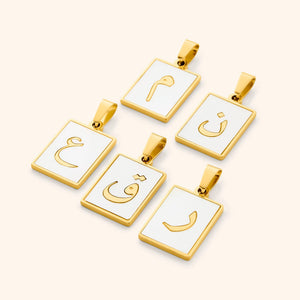 A collection of five Arabic letter charms in 18K gold plating, each featuring an iridescent pearl backdrop. The charms are engraved with Arabic letters.