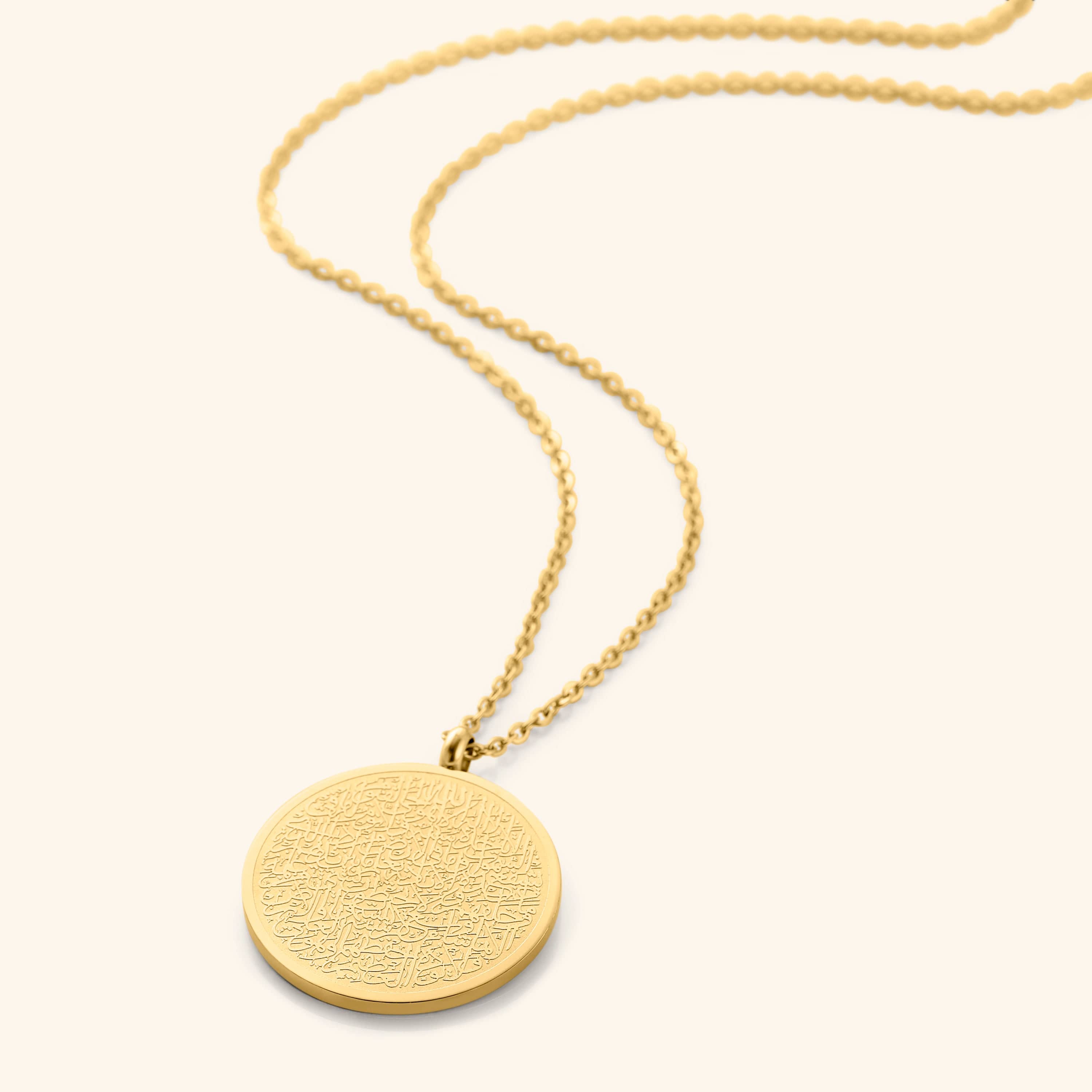 A gold necklace with a round pendant intricately inscribed with Arabic script. The chain is made of small gold beads. The necklace is displayed on a light beige background. Given the inscription and the product name "Ayatul Kursi Necklace," it is highly likely that the script is from the Quran, a central religious text in Islam, suggesting a possible religious significance for the wearer.