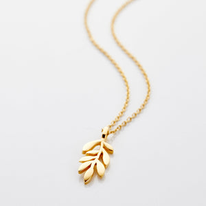 Photo of an 18k gold plated necklace that features chain that is thin and delicate, leading down to a small Olive leaf shaped pendant.