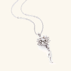 A silver necklace that features a sunflower shaped pendant with Arabic word for ‘happiness’, curving in calligraphy out of the stem of the flower