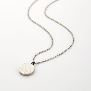 Silver necklace with a circular pendant engraved with 'Maktub' calligraphy, displayed on a white background.