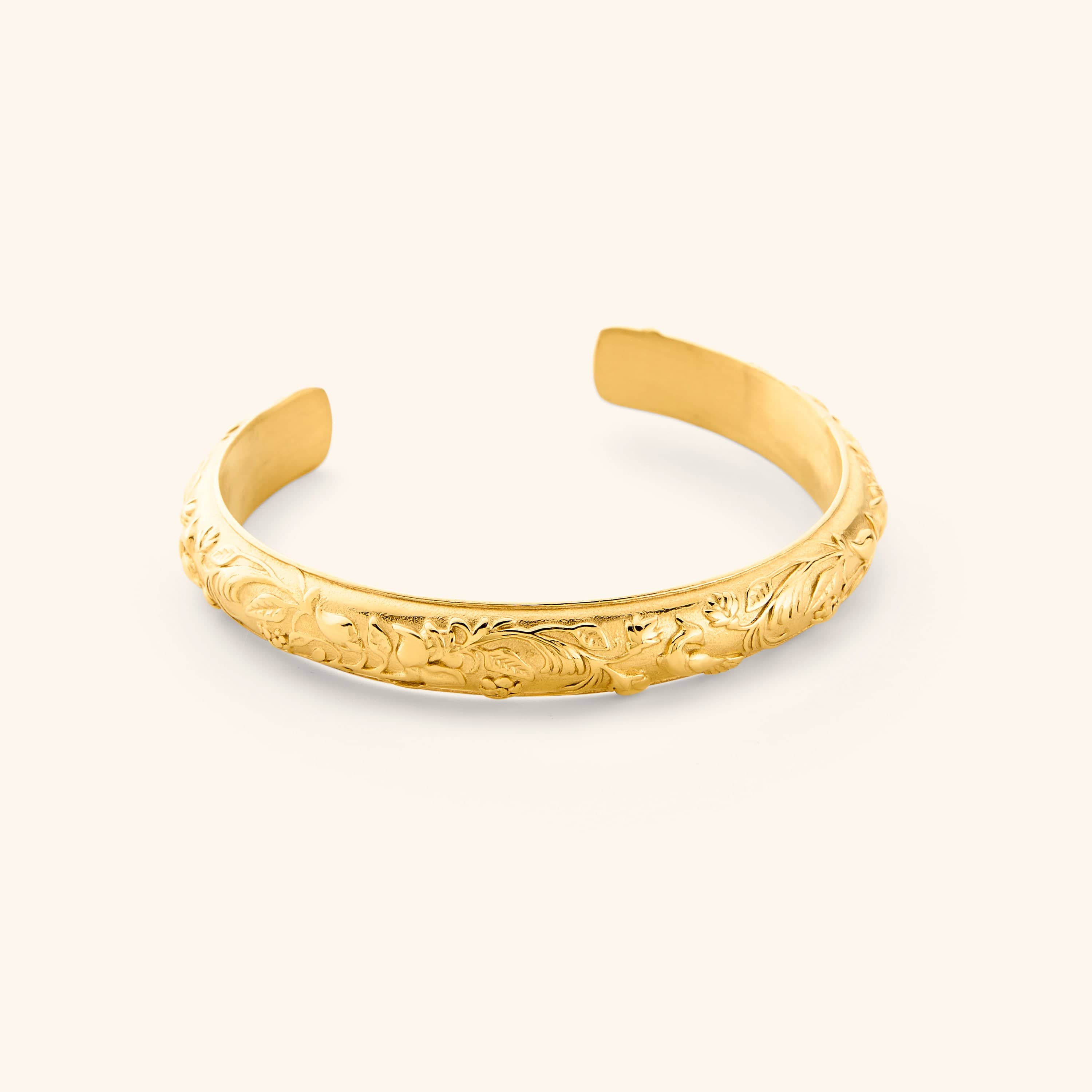 An 18K gold plated cuff etched with jasmine, marigolds, and water lilies art.