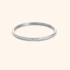 Silver keffiyeh pattern engraved bangle with NOMINAL branding on a light background.