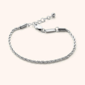 Flat lay of the silver essential rope bracelet that features a woven chain pattern.