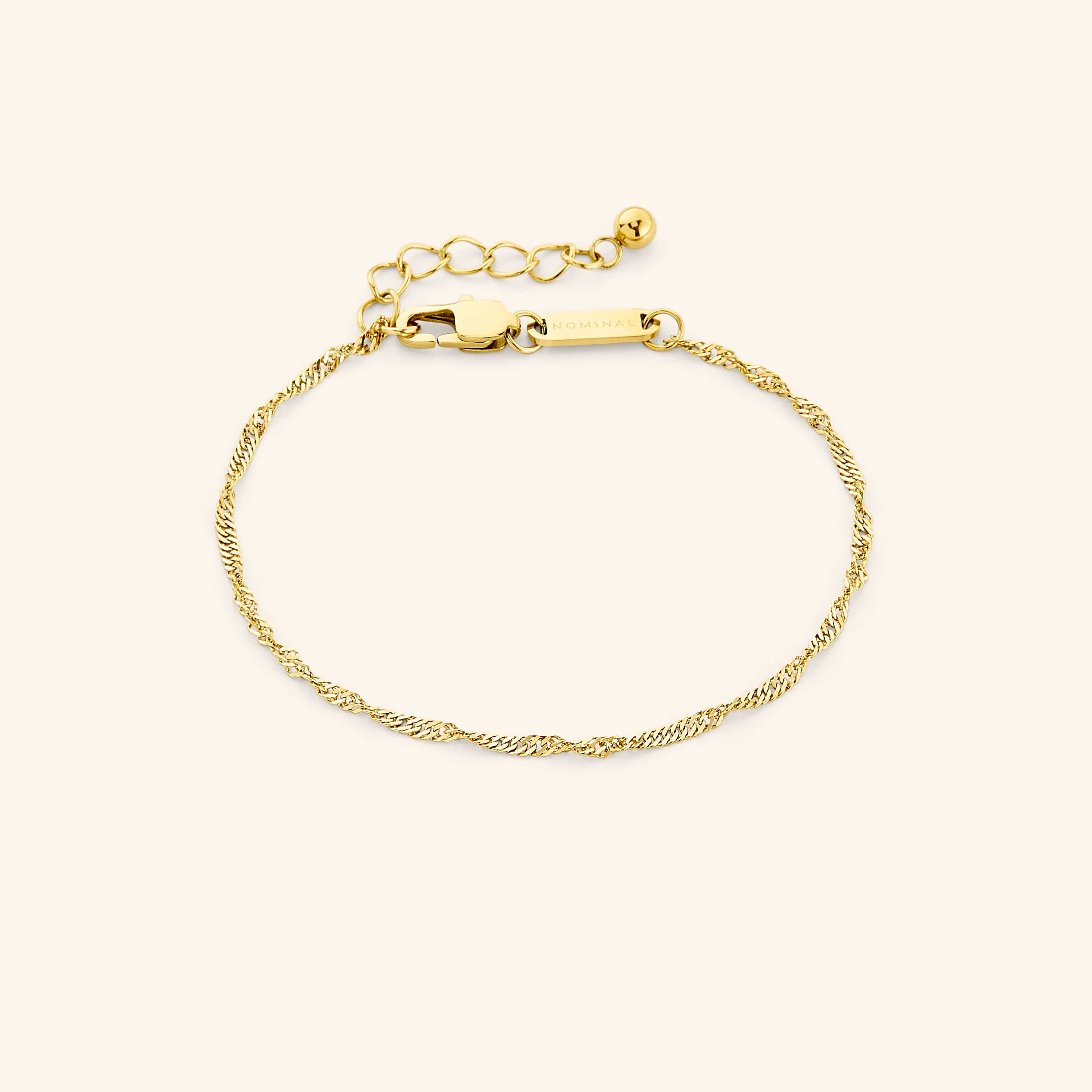 Close-up of the thinnest gold twisted chain bracelet laid flat on a cream background, featuring a lobster clasp and extender chain. Visible text “NOMINAL” engraved on the gold tag.
