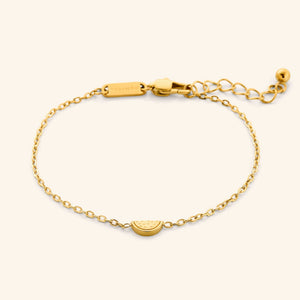 A close-up of the Watermelon Bracelet in 18K gold plating. The bracelet features a delicate cable chain with a small, semi-circular pendant resembling a watermelon slice.