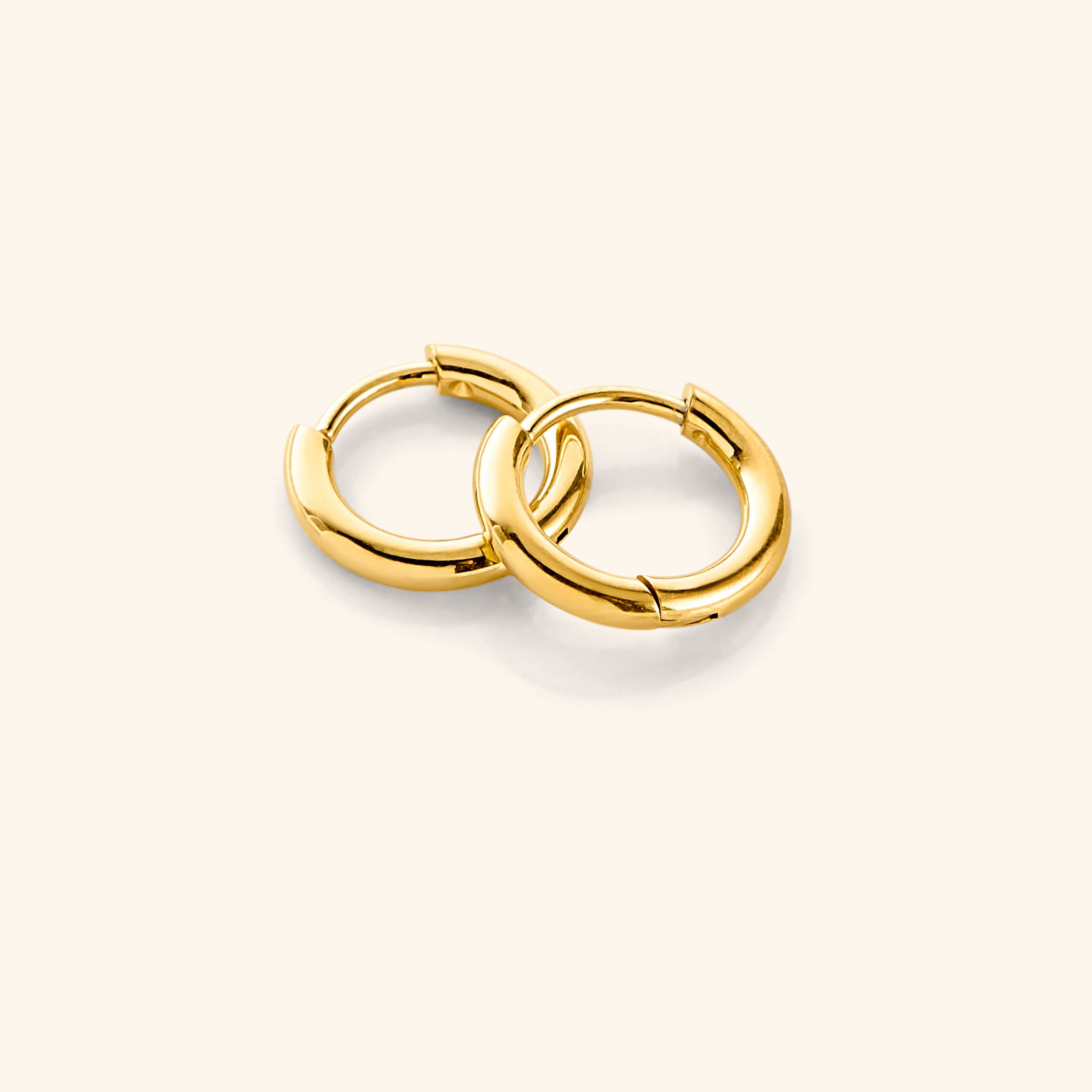 Flat lay of the 18k gold plated Huggie Essential Hoops | 8mm against a white background.