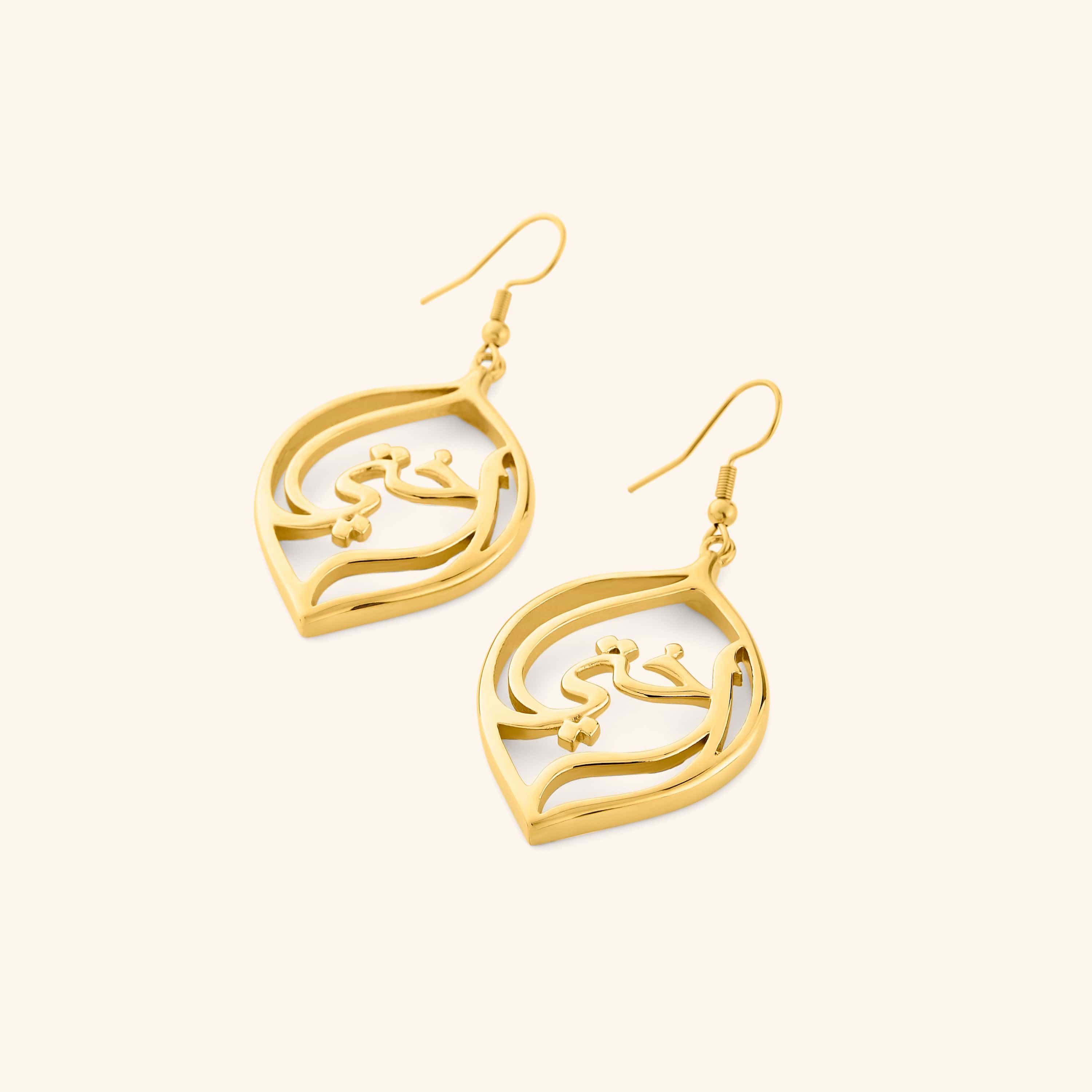A pair of 18k gold plated earrings with a droplet framing the Arabic word for "my sister", أختي (ukhti).