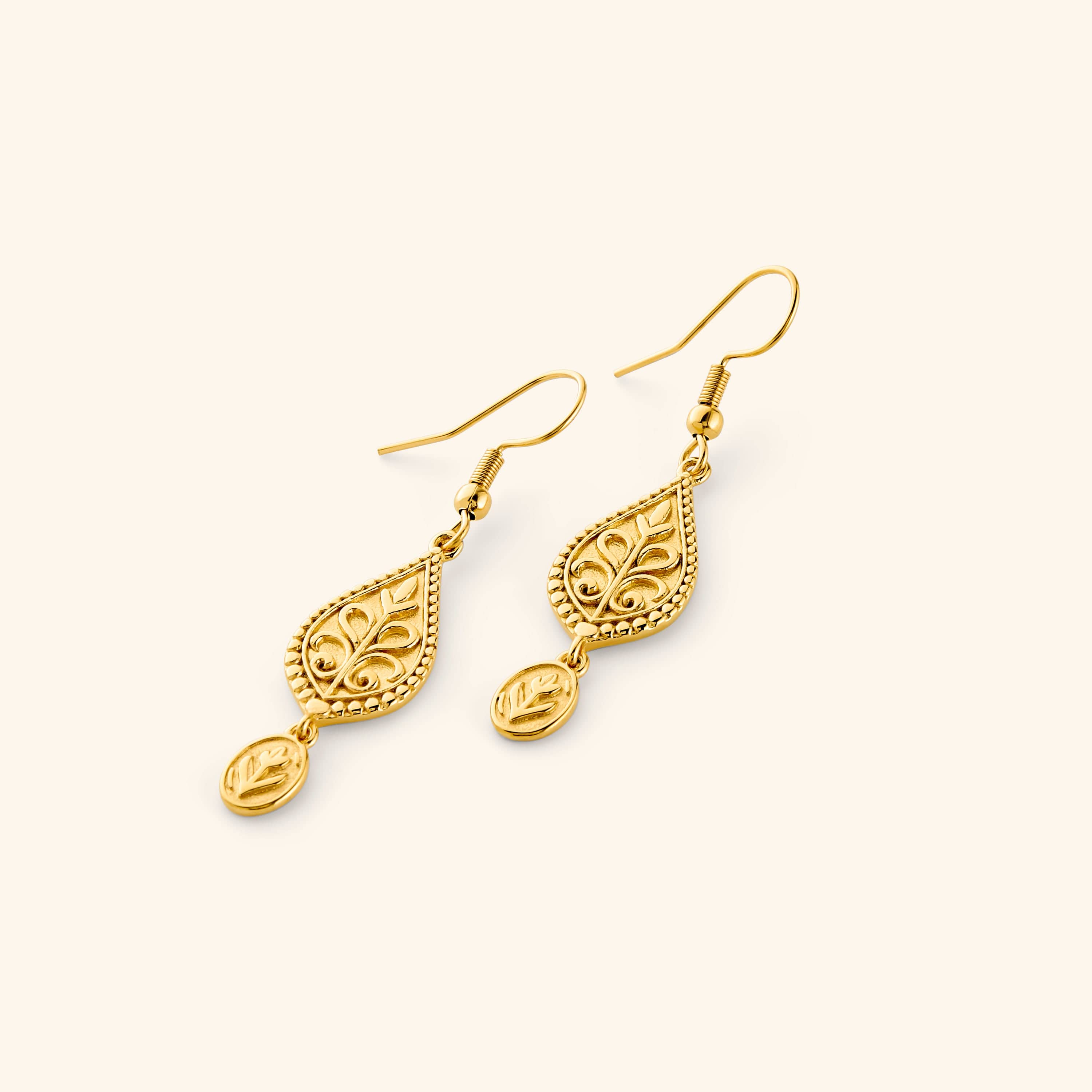 A pair of 18k gold plated dangling earrings featuring Paisley droplets carved with florals and bordered in detailed beading, each one holding a small coin beneath.