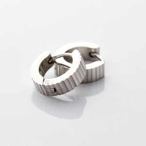 A pair of silver hoop earrings that feature an array of ridges along the outer diameter of these small hugging earrings.