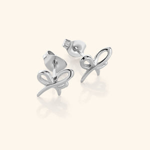 The "Mama" Ribbon Studs in a polished silver finish, showcasing a ribbon-inspired design formed from the Arabic word "ماما" ("Mama"), where the Meem and Alif intertwine to create a bow-like shape. The silver tone offers a sleek and timeless appearance.