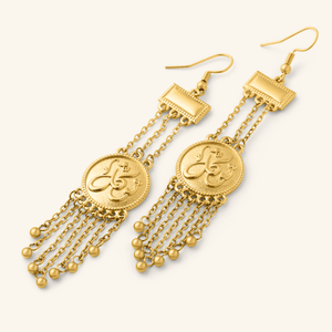 Gold Tawakkul | Trust Raining Earrings shown in a close-up shot, featuring circular coin-style pendants engraved in Arabic calligraphy with multiple dangling gold chains and small bead drops.