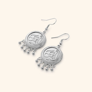 A pair of silver dangling coin earrings that features "my mother" embossed in Arabic Calligraphy design finished with dancing orbs.