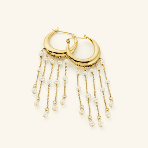 A pair of 18k gold plated earrings crafted in the shape of a delicate crescent, this hoop gracefully extends to embrace a cascade of raining pearls at its bottom.