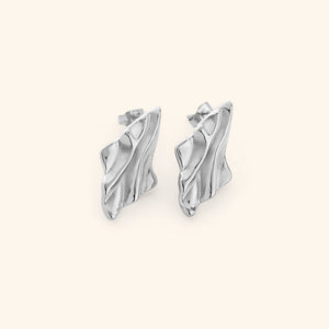Pair of silver earrings with a melted design appearance, on a white background