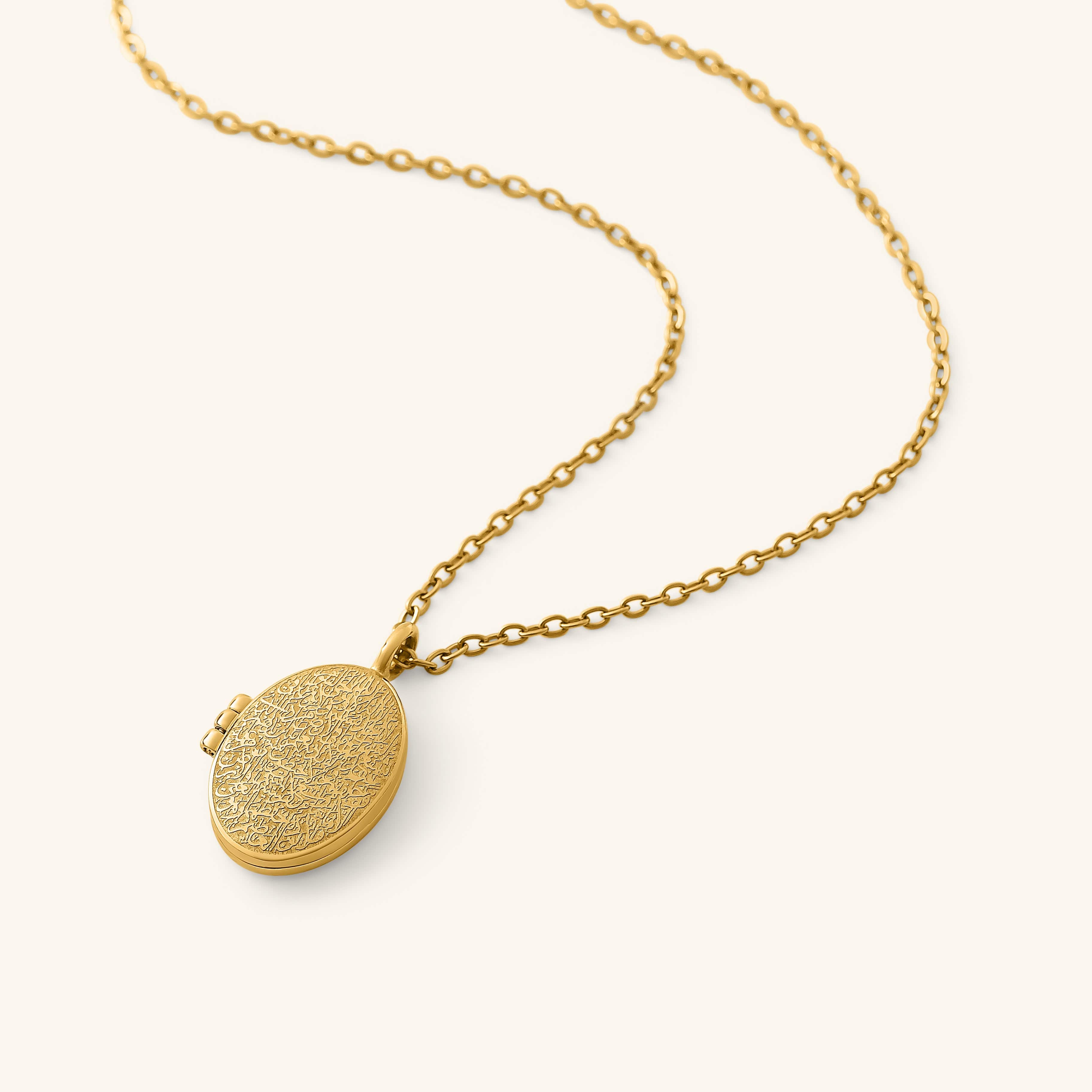 Gold oval locket engraved with detailed Ayatul Kursi calligraphy on the front, hanging from a gold chain on a neutral background.