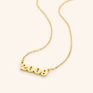 Gold necklace with english number pendant representing birth year, that reads 2009 on a white background
