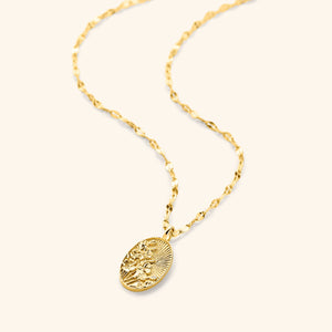 An 18k gold plated necklace that features a molded bouquet of poppies, the national flower of Palestine, on a disc that features sun rays with a vintage finish pendant hanging on a gold plated flutter chain.