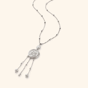 Silver necklace that features a coin pendant stamped with ماما (Mama) in Arabic, suspended from a beaded chain with three strands falling beneath, stamped with a miniature floral at the top.