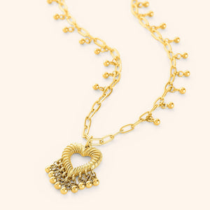 A gold-plated necklace featuring a heart-shaped pendant with three small dangling orbs, displayed on a white background.