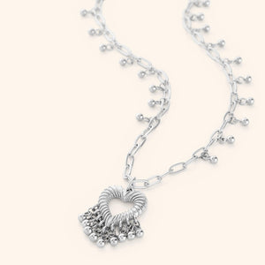 A silver-plated necklace featuring a heart-shaped pendant with three small dangling orbs, displayed on a white background.