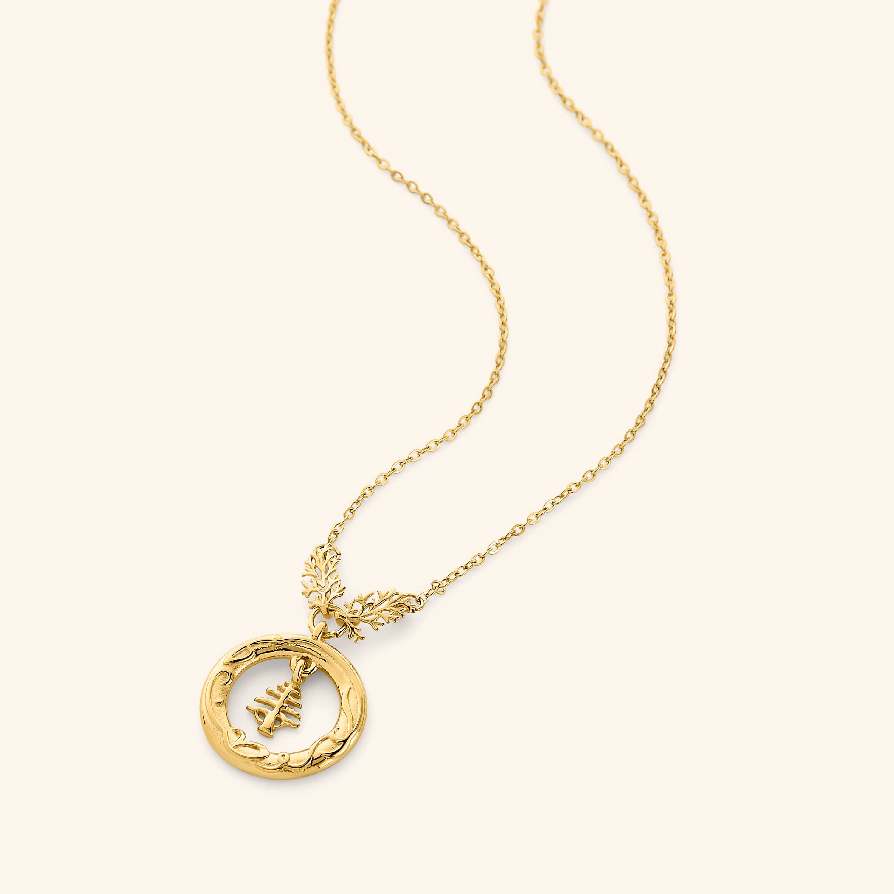 18K gold plated necklace features the Lebanon Cedar tree suspended in a disc that is embossed with "love of the homeland" around the perimeter hanging on a thin gold chain.