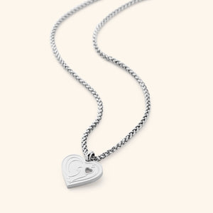 The "Piece of Me" Mama Necklace in a polished silver finish, showcasing a heart-shaped pendant with the Arabic inscription "Ummi" and a tiny heart-shaped cutout, suspended from a sleek wheat chain.