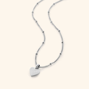 The Mother Love Necklace in a polished silver finish, displaying a heart-shaped charm with the Arabic inscription "Ummi," suspended from a sleek dotted chain, emphasizing its refined craftsmanship.