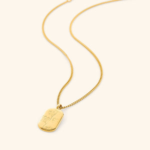 A close-up of the Poppy Stamp Necklace in 18K gold plating, featuring an oval pendant with a raised poppy flower design, symbolizing peace and serenity. The pendant hangs from a delicate gold-plated chain.