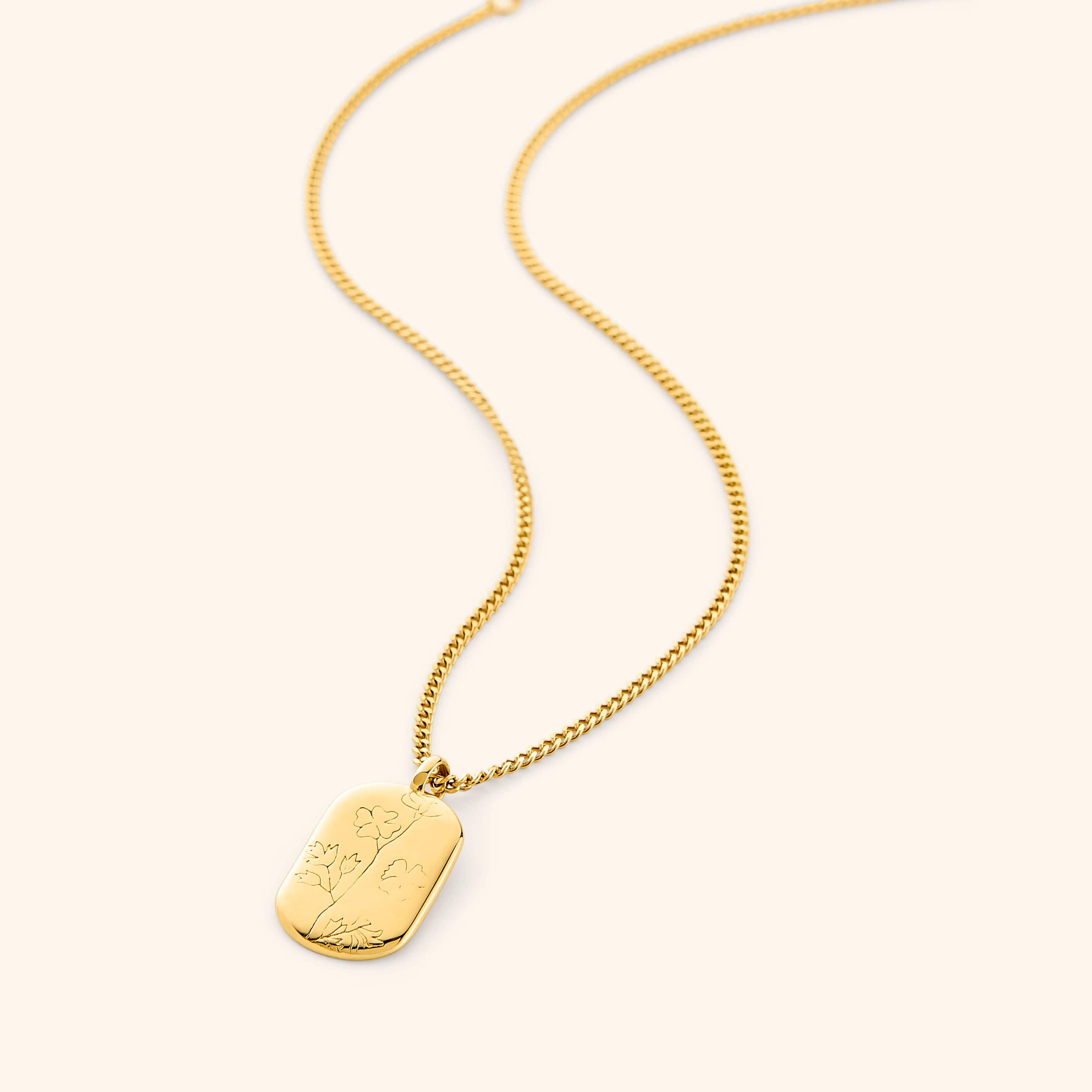 A close-up of the Poppy Stamp Necklace in 18K gold plating, featuring an oval pendant with a raised poppy flower design, symbolizing peace and serenity. The pendant hangs from a delicate gold-plated chain.