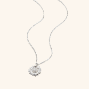 An silver necklace that features a sunflower shaped pendant.