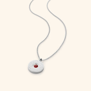 A round silver medallion pendant on a silver chain, featuring a red agate stone in the center with surrounding engraved Arabic calligraphy.
