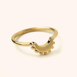 Gold crescent-shaped ring with a smooth curved design accented by small rounded details along the edge, photographed on a neutral background.