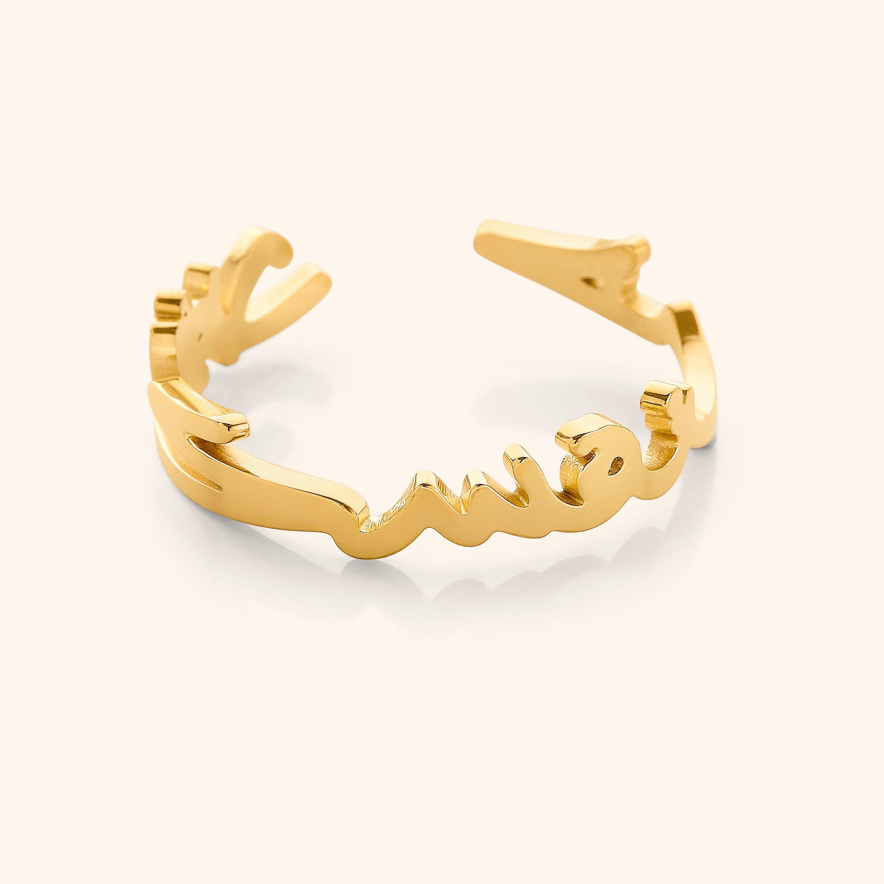 Close-up of a gold ring shaped into Arabic calligraphy spelling "Love Yourself First," on a neutral background.