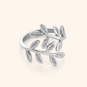 Close-up of a silver ring shaped like intertwining olive branches with engraved leaf details.