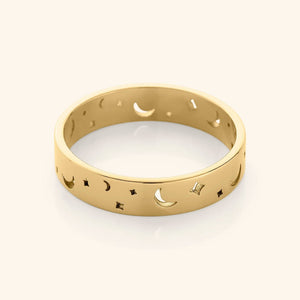 Gold band ring with cutout crescent moons and star shapes, displayed on a plain background.