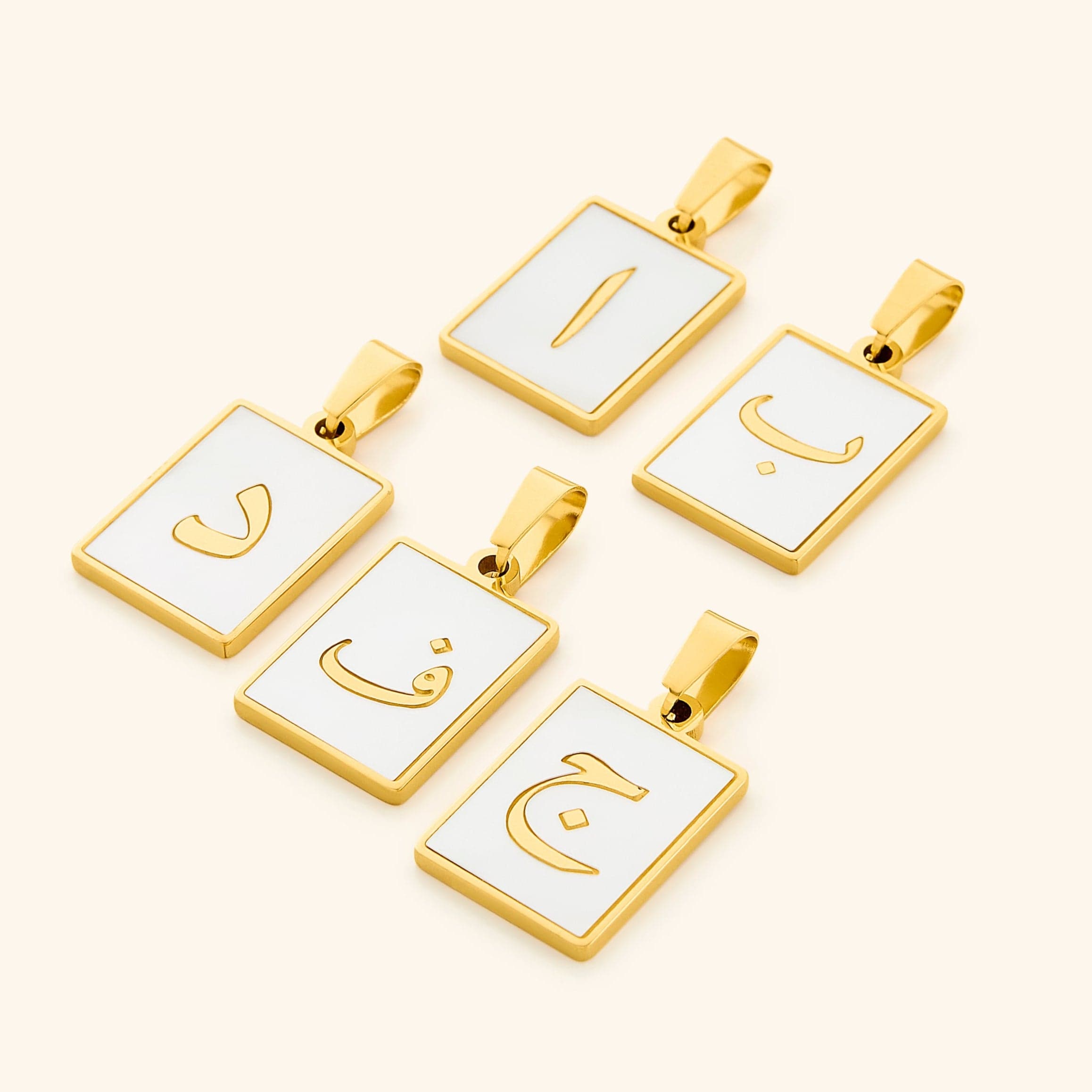 A collection of five Arabic letter charms in 18K gold plating, each featuring an iridescent pearl backdrop. The charms are engraved with Arabic letters: "ا" (A or E), "ب" (B or P), "د" (D), "ف" (F or V), and "ج" (G or J).