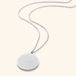 A silver necklace with a round pendant intricately inscribed with Arabic script. The chain is delicate and silver. Given the inscription and the product name "Ayatul Kursi Necklace," it is highly likely that the script is from the Quran, a central religious text in Islam, suggesting a possible religious significance for the wearer.