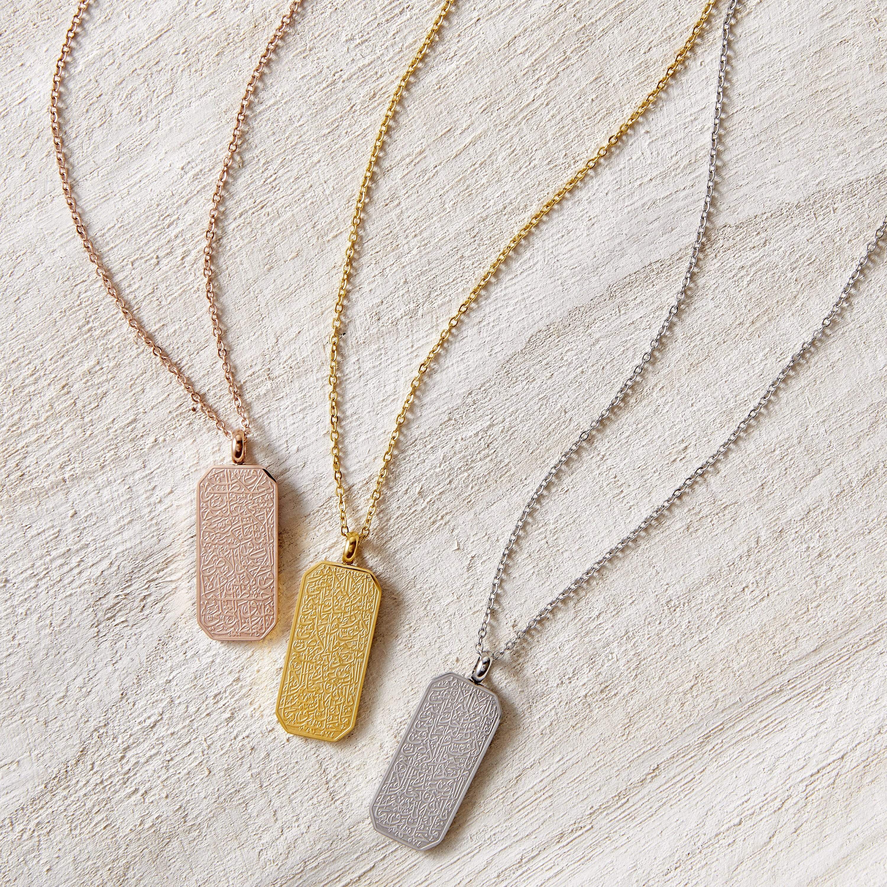 Flat lay of the Ayatul Kursi Tag necklace in three different variations, gold, silver, and rose gold.