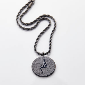 Black car hanger with a circular pendant engraved in Arabic calligraphy of Ayatul Kursi, styled flat on a neutral background.