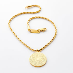Gold car hanger with a circular pendant engraved in Arabic calligraphy of Ayatul Kursi, styled flat against a white background.