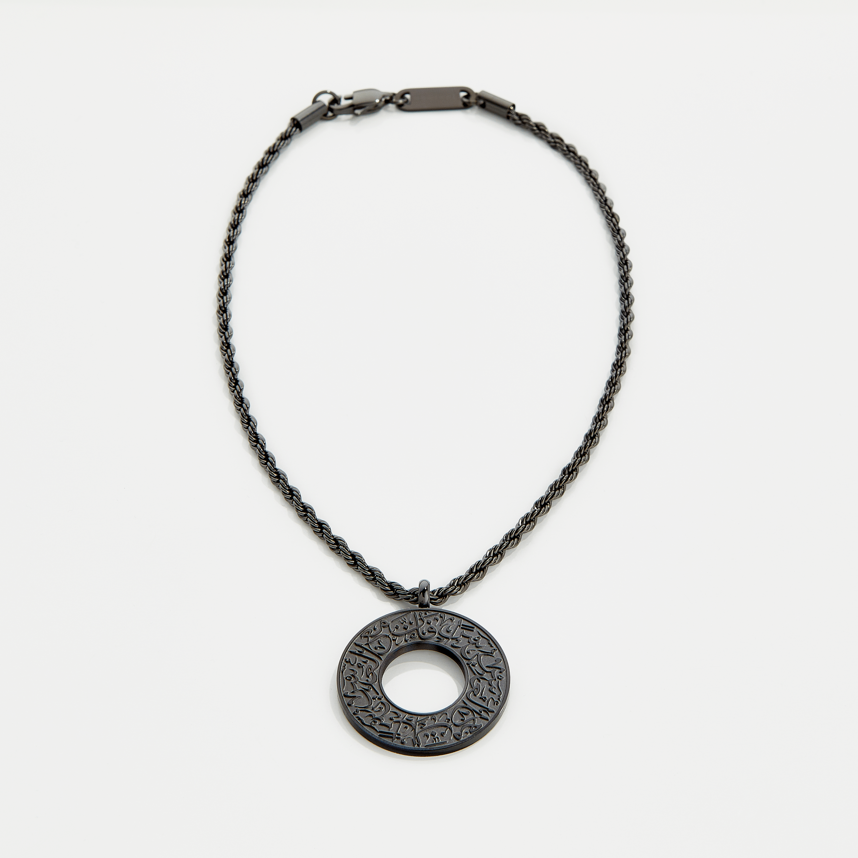 Black car hanger with a circular pendant engraved in Arabic calligraphy reading “With Hardship Comes Ease,” displayed against a neutral background.