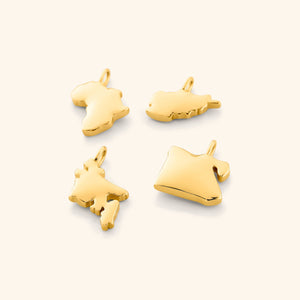 A close-up image showing four gold-plated country map charms arranged side by side on a neutral background, each charm displaying detailed and distinct geographic outlines.