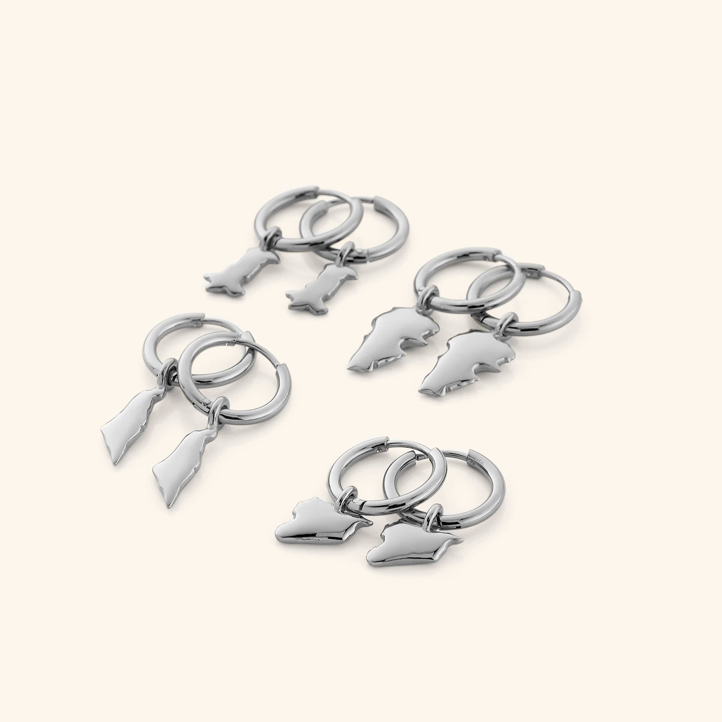 4 different pairs of silver hoop earrings that features outlines of different countries.