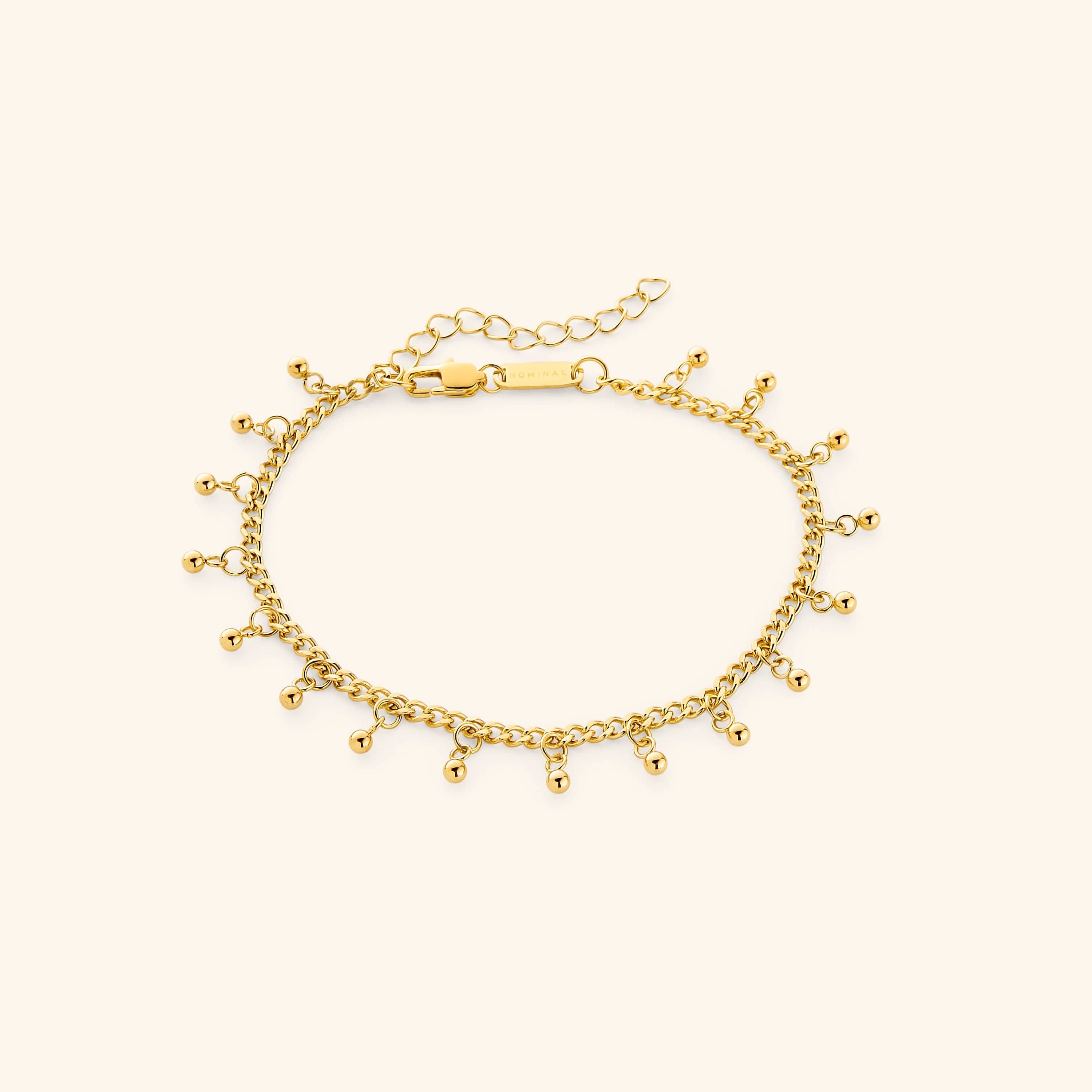 A close-up of the Dangling Dotted Anklet in 18K gold plating. The anklet features a delicate curb chain with evenly spaced 3mm ball-shaped charms that dangle, creating a subtle and elegant design.
