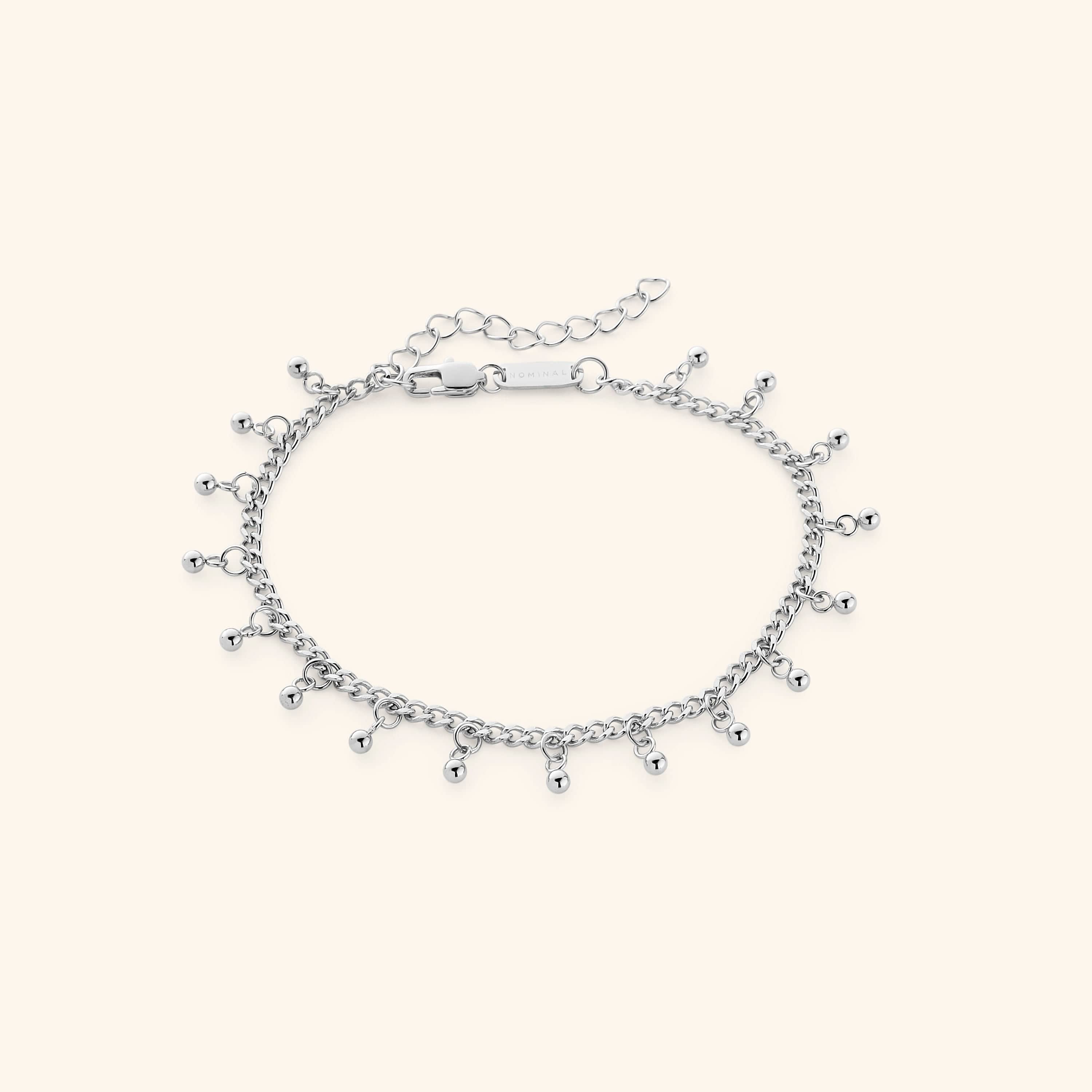 The Dangling Dotted Anklet in a polished silver finish. The anklet showcases a delicate curb chain with evenly spaced 3mm ball-shaped charms that dangle, offering a minimalist and elegant aesthetic.