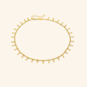 A close-up of the Dangling Dotted Choker in 18K gold plating. The choker features a delicate chain with evenly spaced 3mm spherical bead accents that dangle, creating a subtle and elegant design.