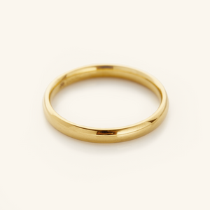 Gold band ring displayed on a soft cream background.