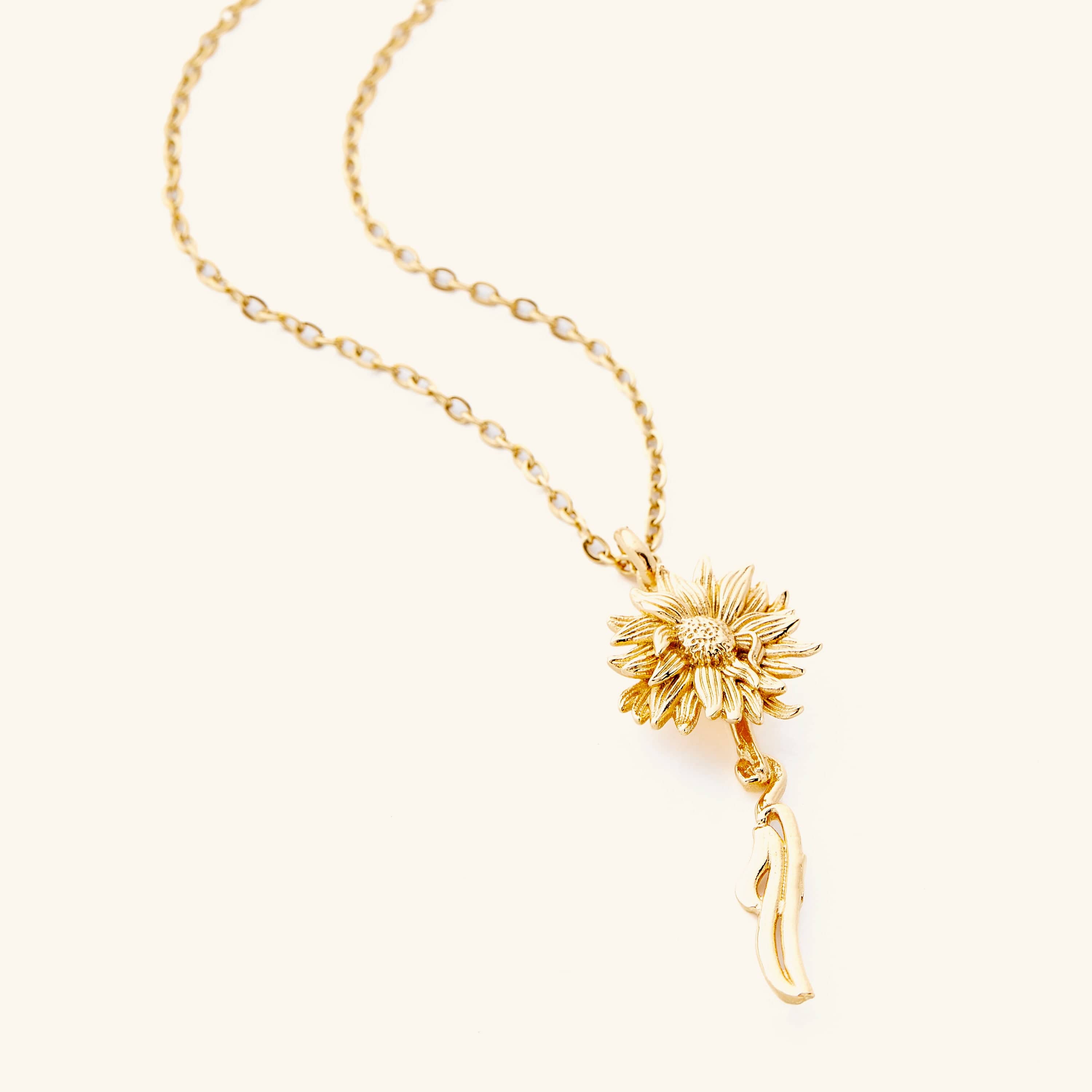 An 18k gold plated necklace that features a sunflower shaped pendant with Arabic word for ‘happiness’, curving in calligraphy out of the stem of the flower